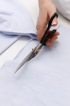 Scissors in hands cut blue cloth Foto stock