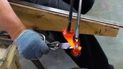 With scissors, he cuts off a piece of red-hot glass. Attaches it to the Video stock 195027172