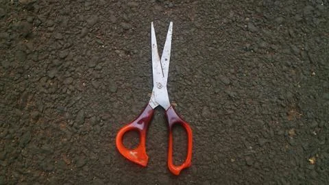 Scissors lying on asphalt Stock Photos