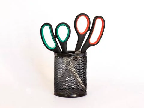 Scissors with a red and green handle in a black metal holder. Isolate Foto stock