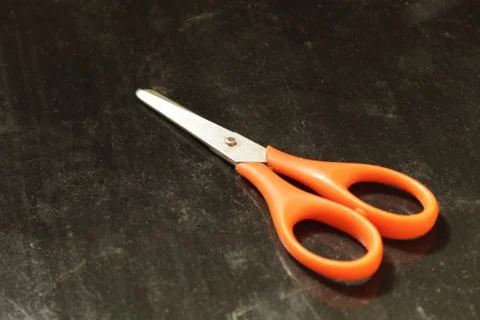 Scissors with a red handle on a black background Stock Photos