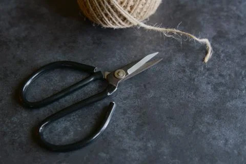 Scissors with rough twine on a grey tile background Stock Photos