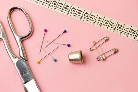 Scissors, sewing pins, thimble and sewing accessories on a pink background Illustration