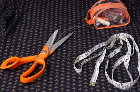 Scissors tailor and inch, centimeter tape on a background of blue fabric with Stock Photos