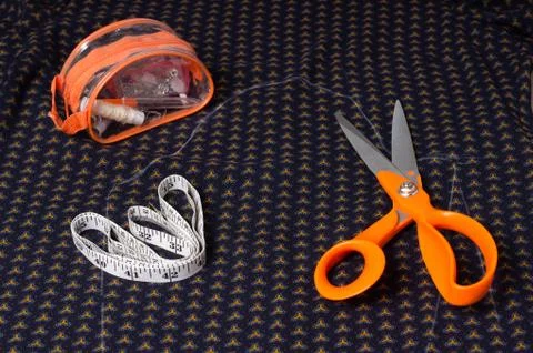 Scissors tailor and inch, centimeter tape on a background of blue fabric with Stock Photos