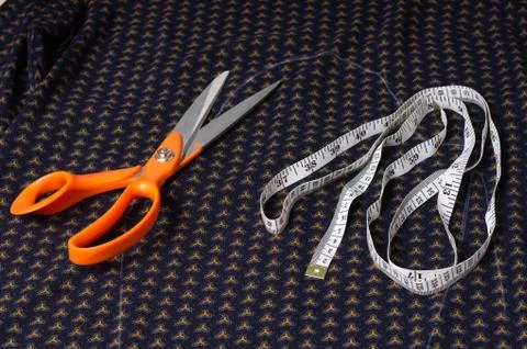 Scissors tailor and inch, centimeter tape on a background of blue fabric with Stock Photos