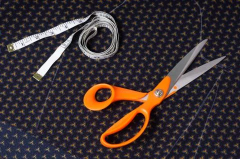 Scissors tailor and inch, centimeter tape on a background of blue fabric with Stock Photos