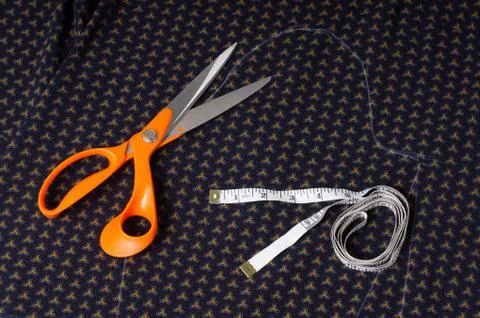 Scissors tailor and inch, centimeter tape on a background of blue fabric with Stock Photos
