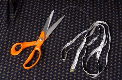 Scissors tailor and inch, centimeter tape on a background of blue fabric with Stock Photos