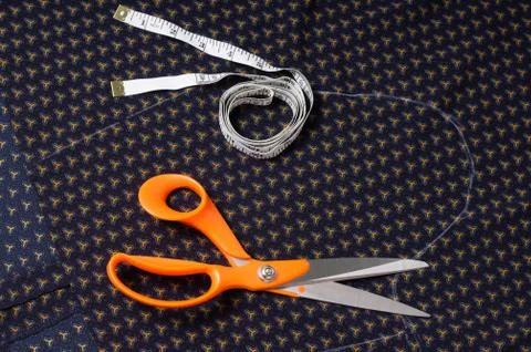 Scissors tailor and inch, centimeter tape on a background of blue fabric with Foto stock