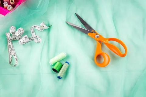 Scissors tailor and inch, centimeter tape and green threads on a background o Stock Photos