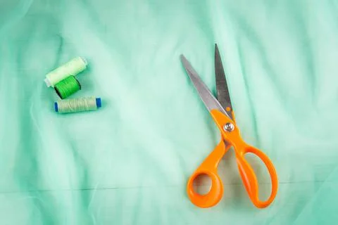 Scissors tailor and inch, centimeter tape and green threads on a background o Stock Photos