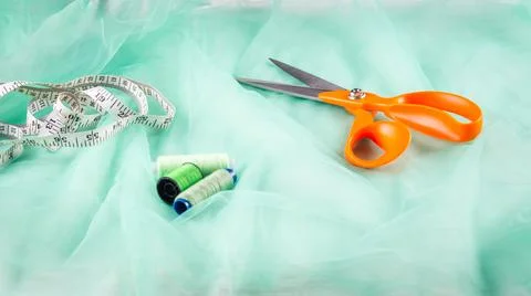 Scissors tailor and inch, centimeter tape and green threads on a background o Stock Photos