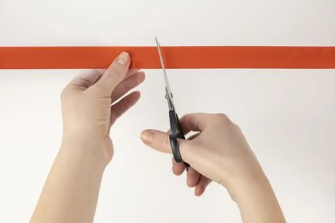 Scissors in a woman's hands cut a red ribbon. Ribbon cutting ceremony. Stock Photos