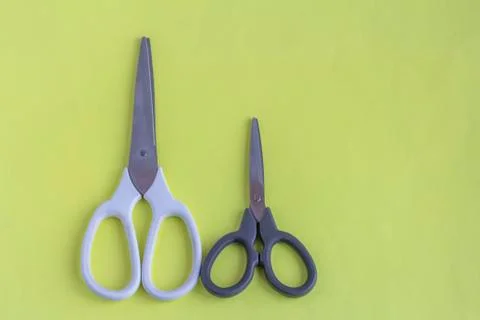 Scissors on a yellow background.White large and black small scissors for work 写真素材