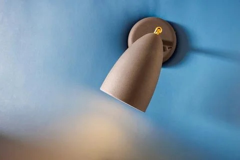 Sconce with light on at the head of the bed. Blue, leather headboard. Cozy,.. Stock Photos