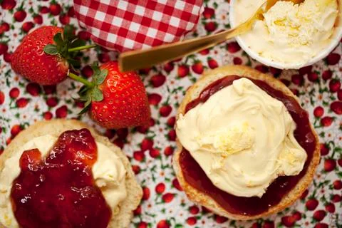 A scone split in half topped with clotted cream and strawberry jam Stock Photos