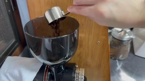 Scoop coffee beans into the automatic coffee grinder at home Видео 249374395