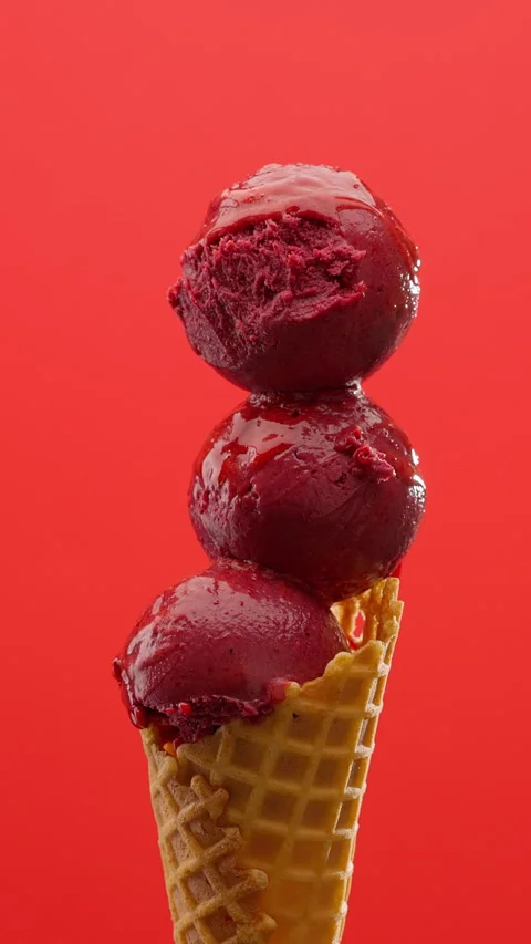Scoop fruit ice cream into waffle cone on a vibrant red background. Vertical Stock Footage 312380599