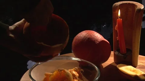 Scoop pumpkin flesh with a spoon to a plate, candle in candlestick on background Stock Footage