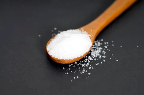 Scoop of white sugar on black background Stock Photos