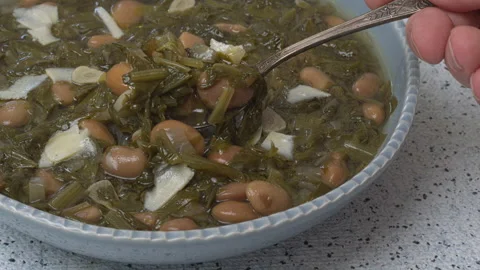 Scooping chicory and bean soup with a spoon. Stock Footage 312113617