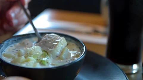 Scooping Chunky Fish Chowder in Cozy Restaurant Setting Stock Footage 318634861