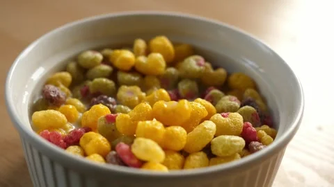 Scooping colorful fruity cereal with a spoon from a bowl full of milk Stock Footage 294697702
