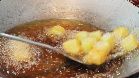 Scooping crispy golden potato chunks out of deep frying oil. 動画素材 344556343
