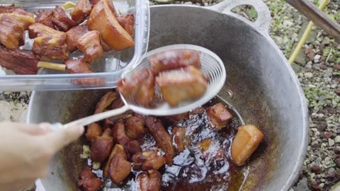 Scooping Deep Fried pork in hot oil on a big pan Video stock 310017998