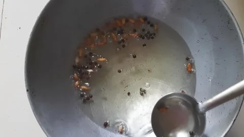 Scooping Garlic and Black Pepper Tempering with Spoon Stock Footage 337353875