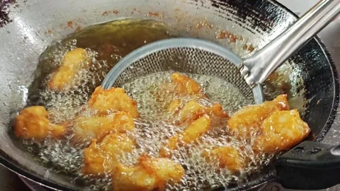 Scooping up golden brown crispy fried fish with a mesh strainer. Stock Footage 342690575