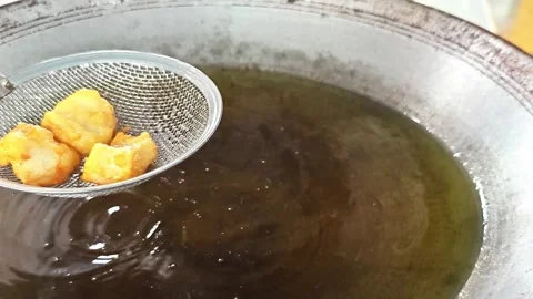 Scooping up golden crispy fried fish from oil with a strainer. Vídeo Stock 342695836