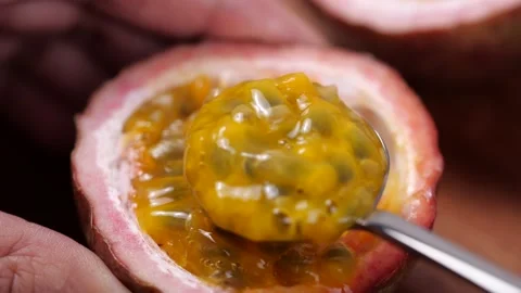 Scooping the inside of a fresh passion fruit. Fresh Fruit for healthy eating Stock-Footage 142774981