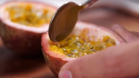 Scooping the inside of a fresh passion fruit with a spoon Video stock 142914974