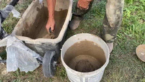 Scooping Mixed Clay from Large Container into Bucket Stock Footage 316539390