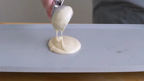 Scooping pancake batter onto a hot griddle. Stock Footage 138339587