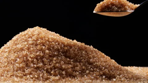 Scooping pure brown sugar from a mound of cane sugar with a spoon. Stock Footage 254133827