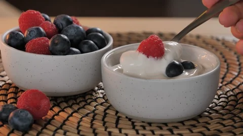 Scooping spoon yogurt.  Bowl of ripe fresh berries (raspberries, blueberries), Stock Footage 124046845
