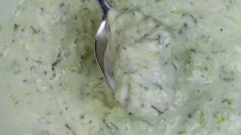 Scooping yogurt garlic dip with spoon showing swirl motion in thick white Stock Footage 314363381