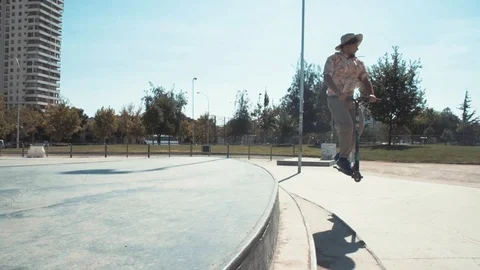 SCOOTER RIDER DOING A BAR SPIN, A FULL SPIN AND MORE TRICKS IN SKATE PARK Stock Footage 102401539