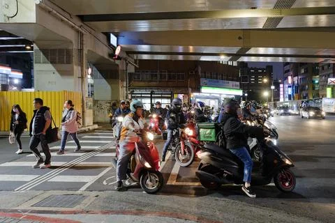 Scooters and Uber Eats Rider Waiting at Red Light Under Taipei Bridge Night Photos