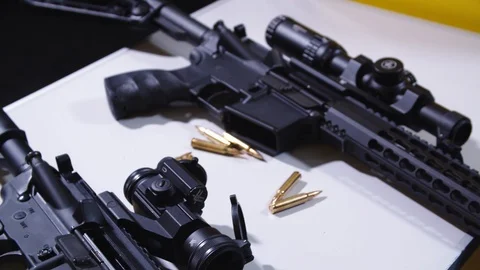 Scoped assault rifles with bullets on a white table in shooting range. Video stock 122237566
