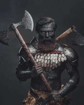 Scorched barbarian holding axe and staring to camera in dark background Stock Photos