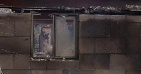Scorched water heater seen through a broken window behind drifting smoke Stock Footage 59515472