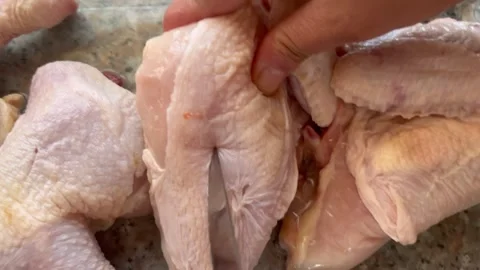 Scoring Raw Chicken Pieces with a Knife for Marination Stock Footage 345320739