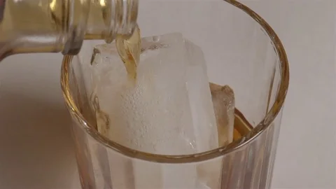 Scotch on the rocks in slow motion. Pouring whiskey over ice in a glass. Stock Footage 71215468
