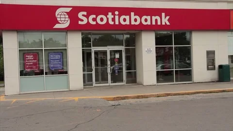 Scotiabank store with customer pedestrian exiting, cars and traffic scooter pass Stock Footage 247142802