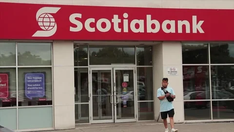 Scotiabank store with customer pedestrian exiting, cars and traffic passing Stock Footage 247142806