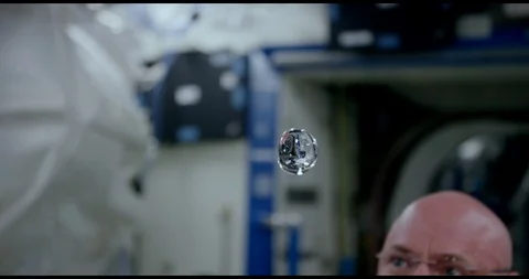 Scott Kelly extracts a floating ball of water and inserts coloured ink - 2015 Stock Footage 95816457
